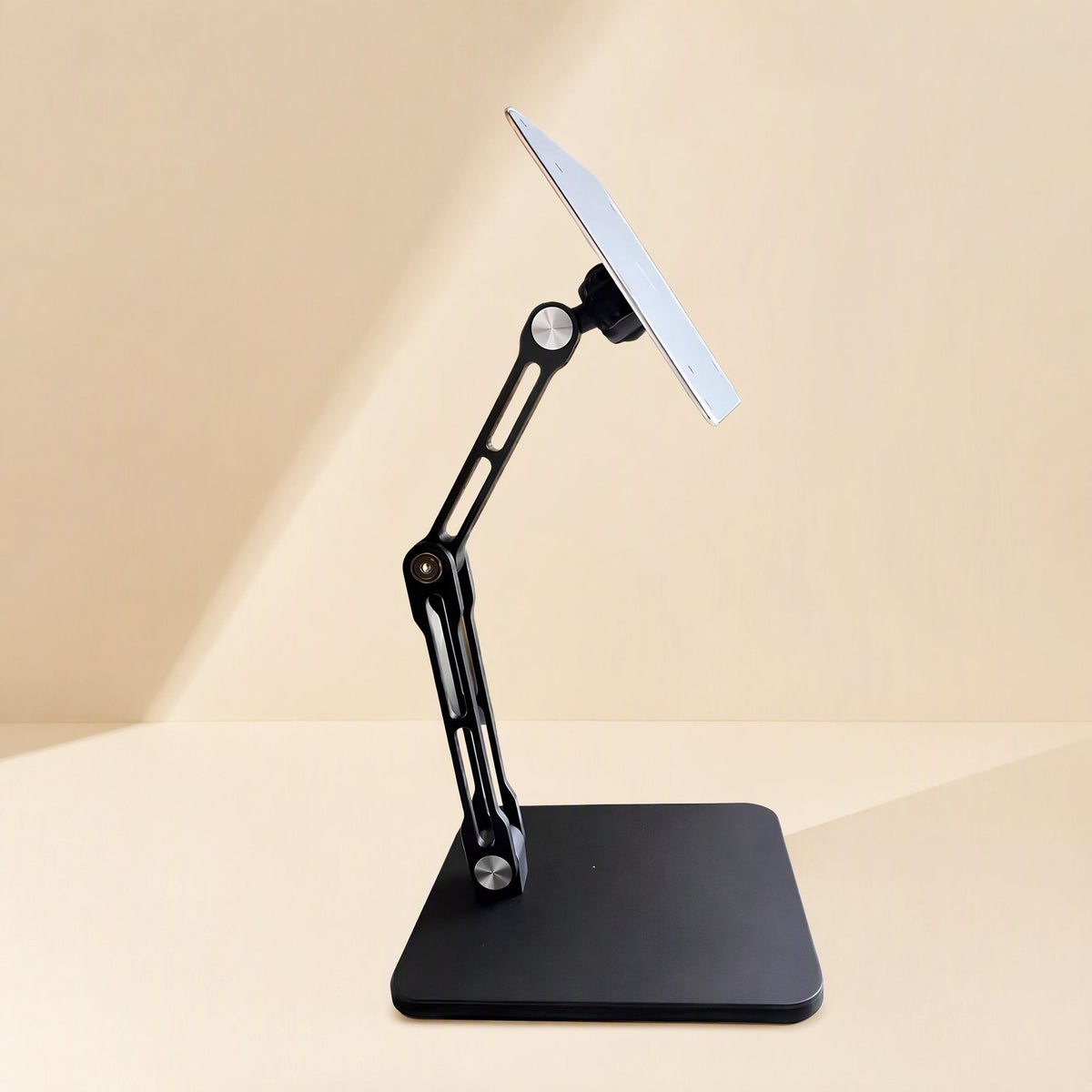 Swiveldesk – Side view of the black stand with a silver-faced square base and a tilted mounting plate on a folded arm