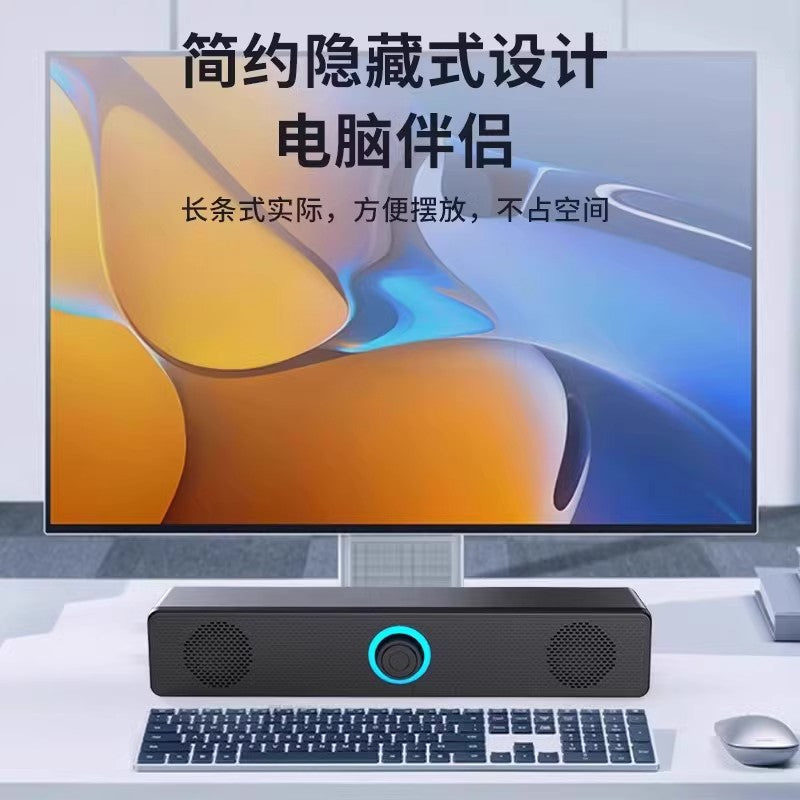 Wavecrest – Black soundbar speaker with blue-lit knob placed below a monitor, in front of a keyboard and mouse