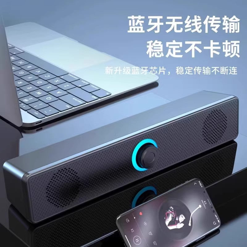 Wavecrest – Slim black speaker bar with blue glowing dial on a desk next to a laptop, a phone playing music in front