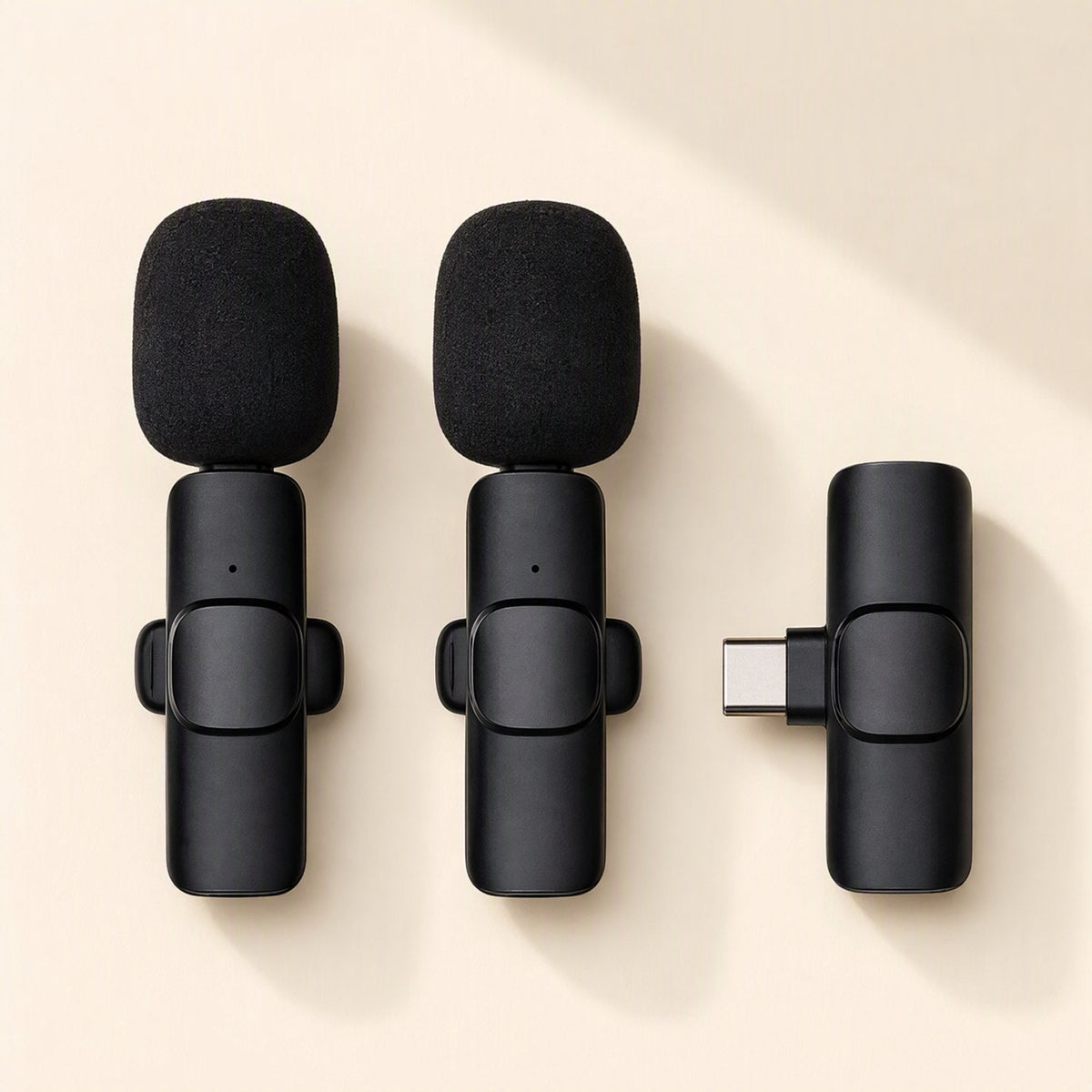 Freevoice – Two black lavalier mics with foam windscreens next to a USB-C receiver on a light backdrop