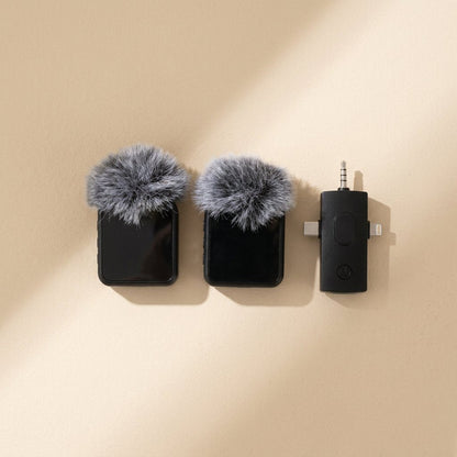 Voicepin – Overhead view of two transmitters with fluffy windscreens beside the black receiver with 3.5mm plug