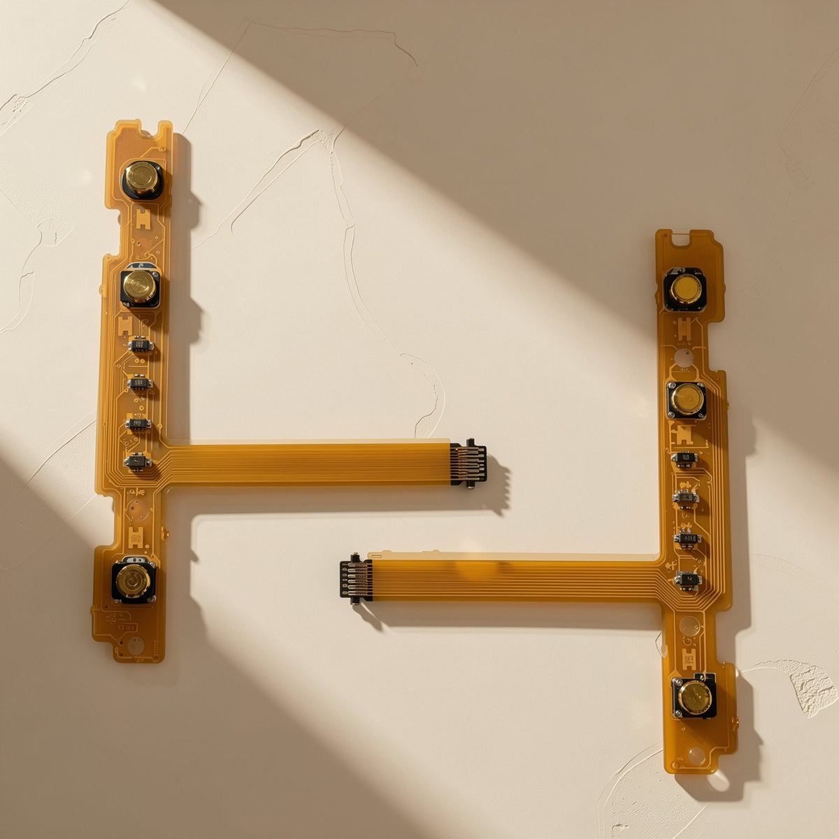 Joylink – Pair of orange SL/SR button flex cables with connectors laid flat on a cream textured surface