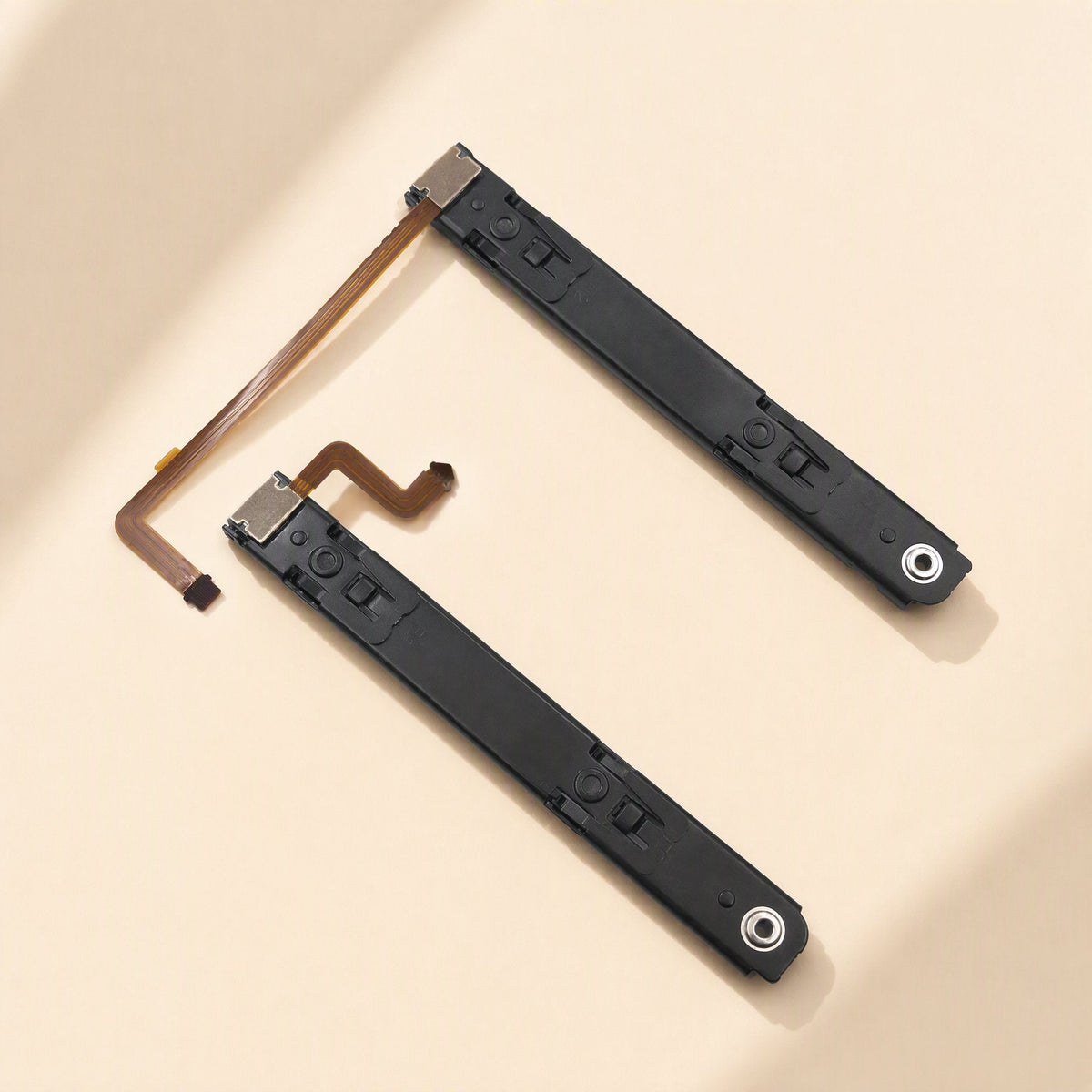 Railglide – Two black slide rails with flex cables laid out diagonally in an L shape on a cream surface