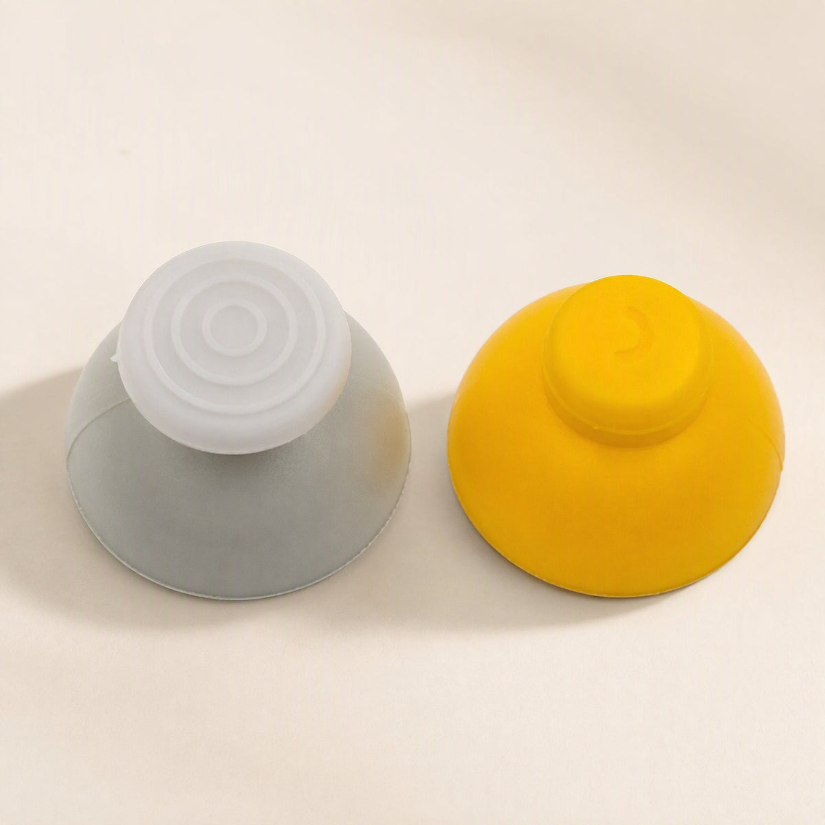 Rockergrip – Gray and yellow rocker caps side by side from the side, showing dome tops with textured and smooth finishes