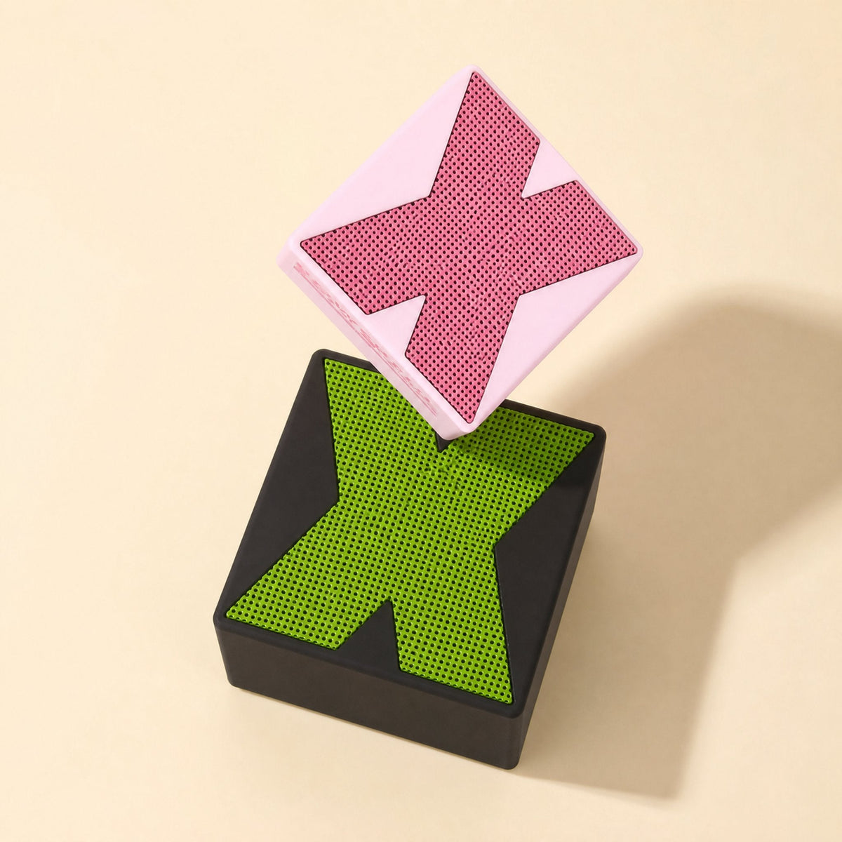 Meshsound – Pink speaker tilted on top of a black speaker with a lime green X mesh grille, shown from above