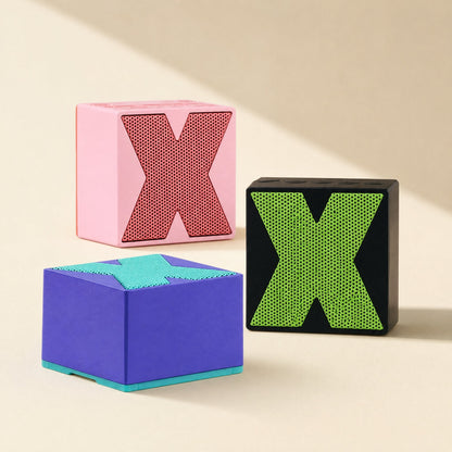 Meshsound – Pink, black and purple cube speakers arranged in a group, X grilles facing front and top on a beige backdrop
