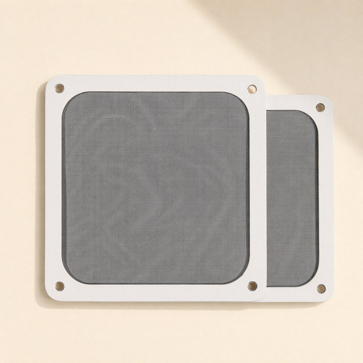 Dustflow – Two white-framed square mesh dust filters with corner screw holes on a cream background