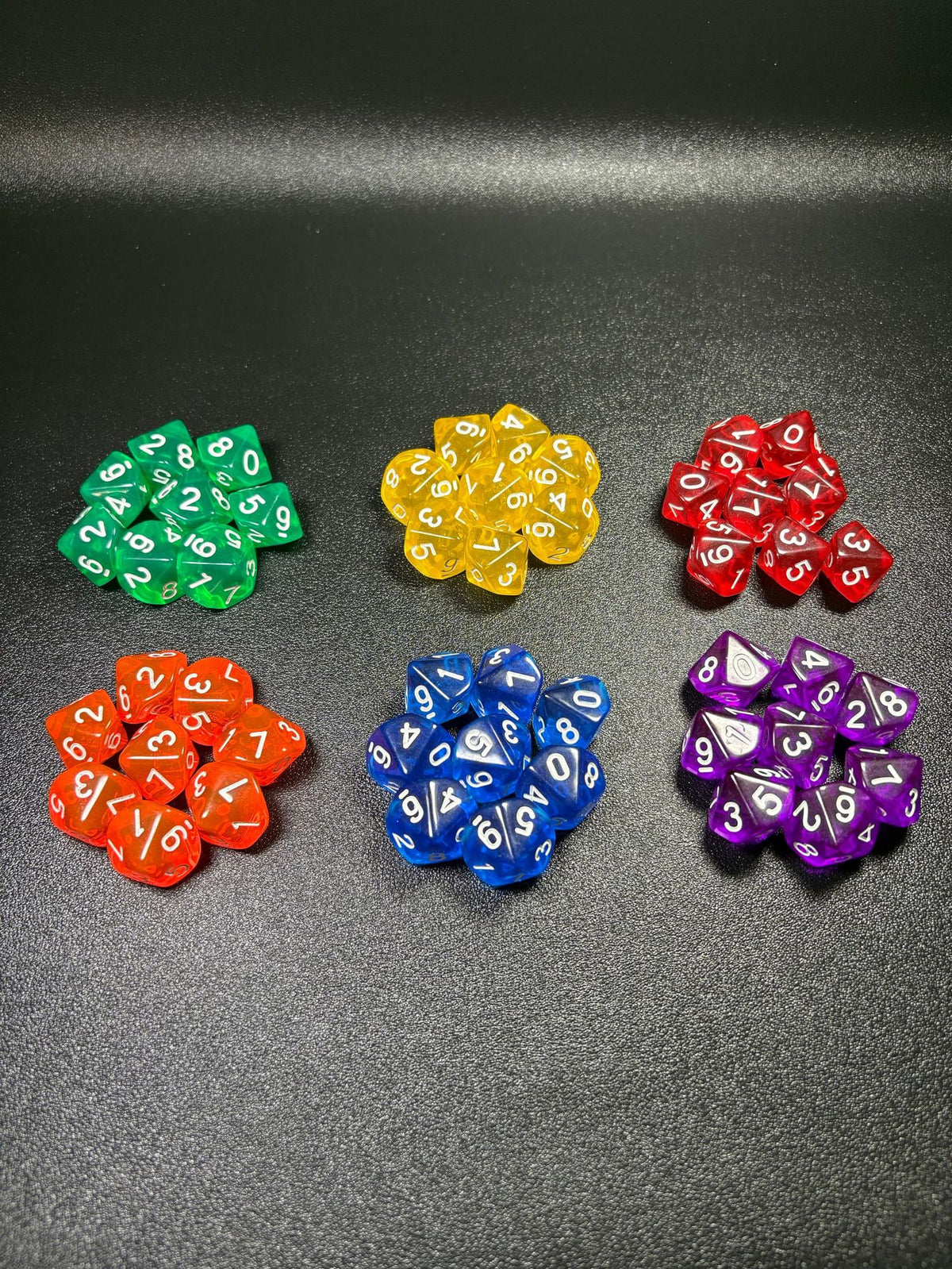 Prismdot – Two rows of transparent ten-sided dice piles: green, yellow, red, orange, blue and purple on black