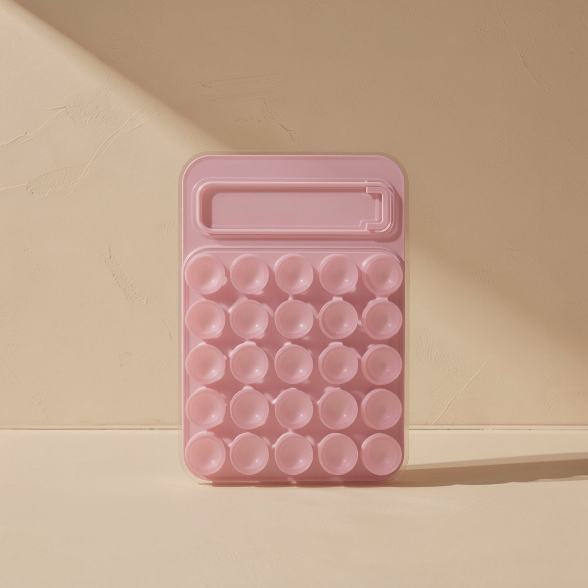 Gripcup – Pink silicone pad showing a grid of 25 suction cups above the folded kickstand slot, on a cream surface