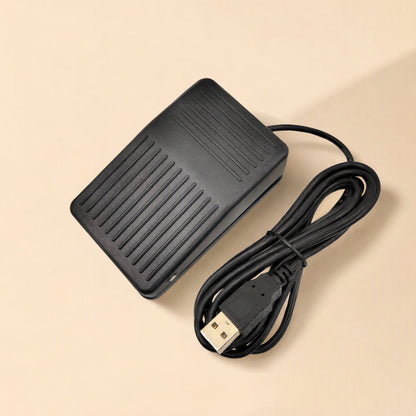 Tapstep USB Foot Pedal Switch in black with coiled USB cable on a beige background, top view