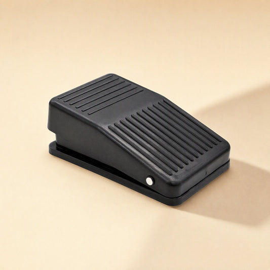Tapstep – Black foot pedal switch seen from the side, showing ribbed pedal surface and silver side button