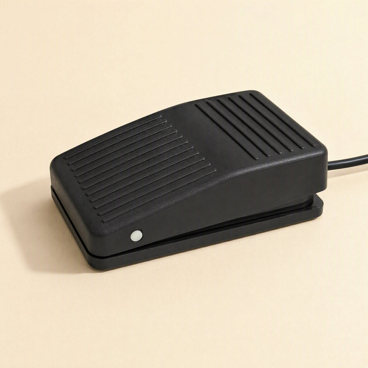 Tapstep – Close-up of the black foot pedal's sloped ridged surface and small white indicator light on the front corner