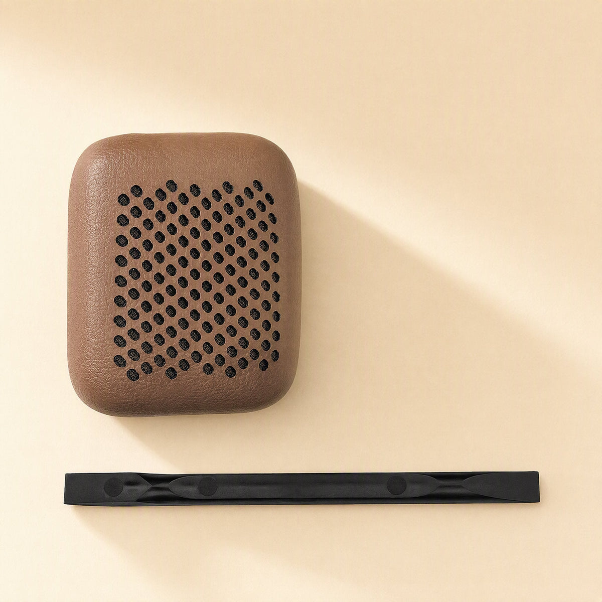 Earsoft – Single brown perforated ear pad cover beside a black plastic pry tool on a cream surface