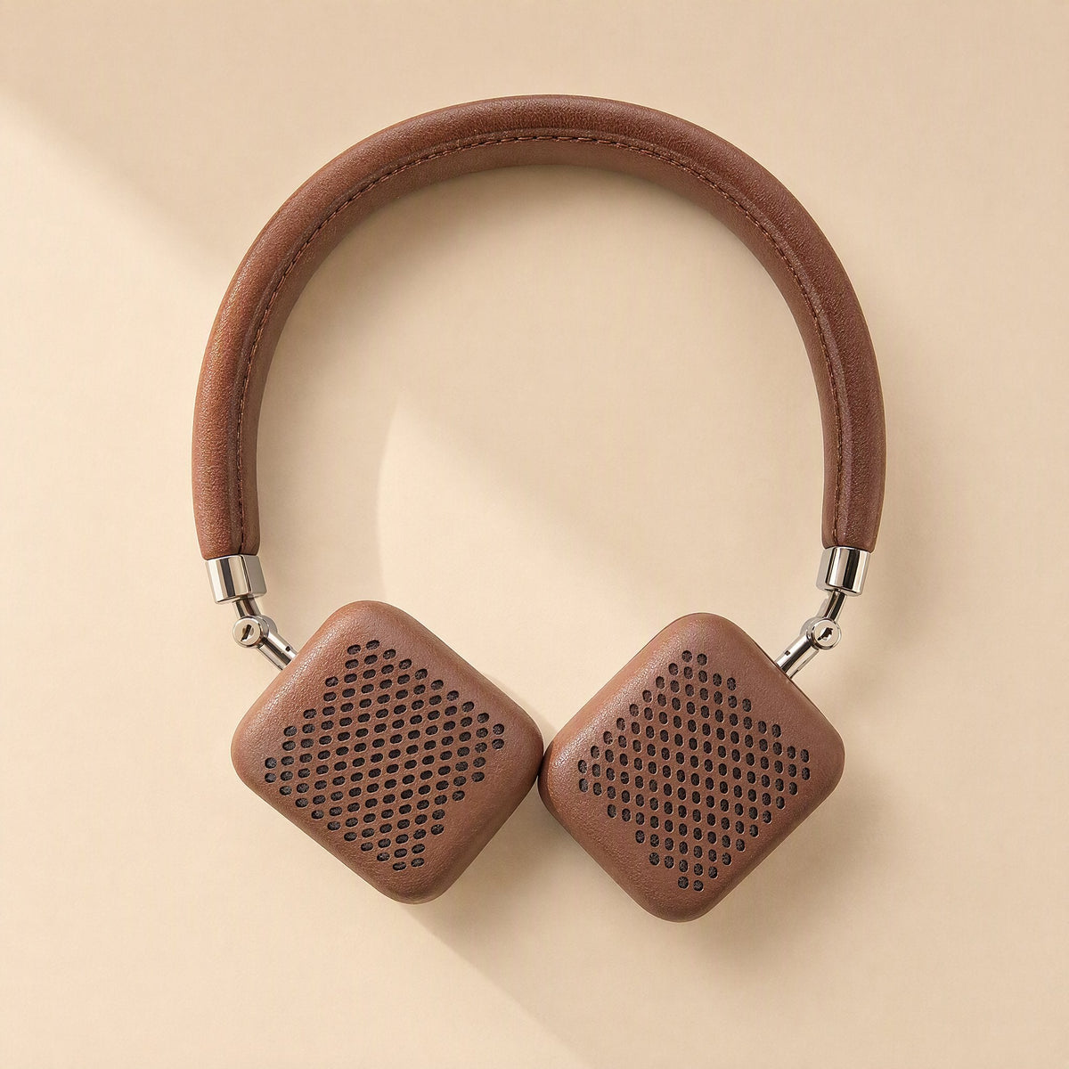 Earsoft – Brown on-ear headphones with the perforated brown leather ear pad covers fitted, on a cream background