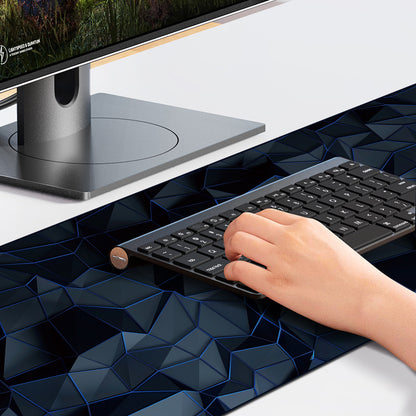 Cursorloom – Hand resting on a keyboard on a dark blue low-poly mouse pad beside a monitor on a white desk
