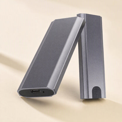 Driveguard – Two gray enclosure halves leaning together, one end showing the USB-C port and a small indicator hole