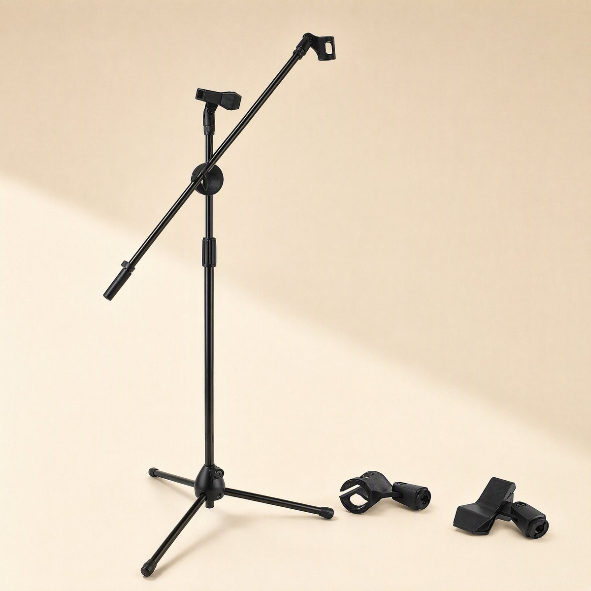 Tripodrise – Black tripod stand with angled boom arm beside two detached black microphone clips on a beige background