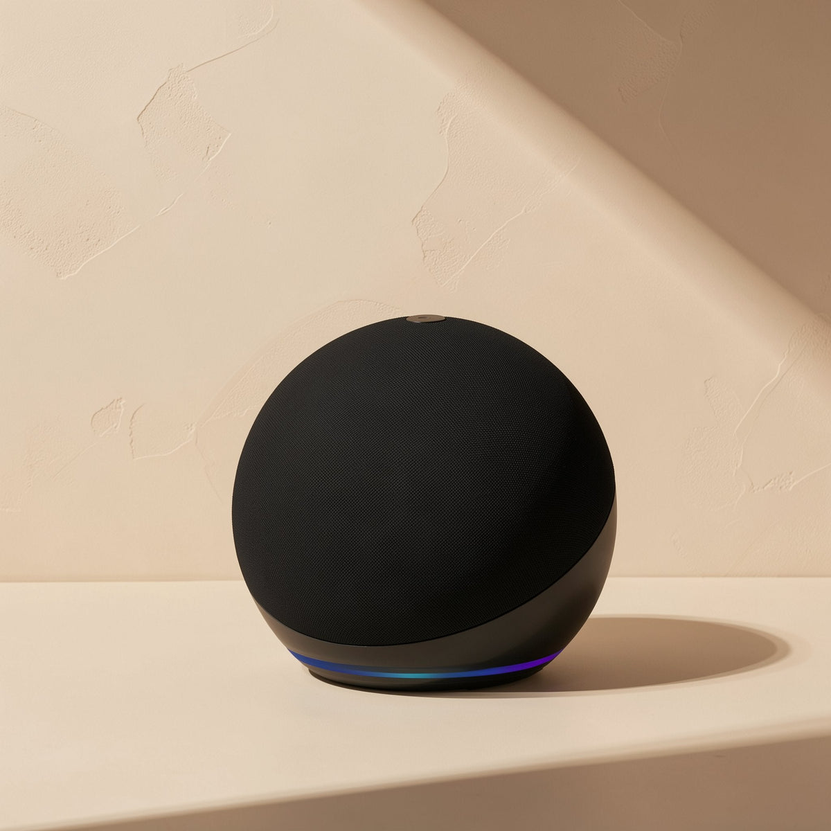 Roamnote Mini Bluetooth Speaker in black with a glowing blue light ring on a beige shelf in angled sunlight