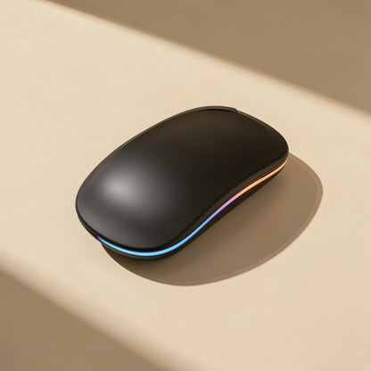 Roamclick Silent Wireless Laptop Mouse in matte black with a glowing rainbow LED strip, in warm window light